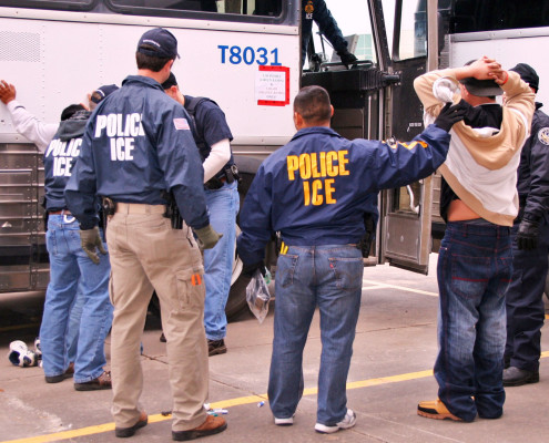 U.S. Immigration and Customs Enforcement Agents transporting suspects after a raid